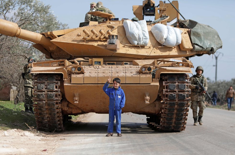 Un nio sirio hace el signo de la victoria frente a un tanque turco en Idlib el 20 de febrero