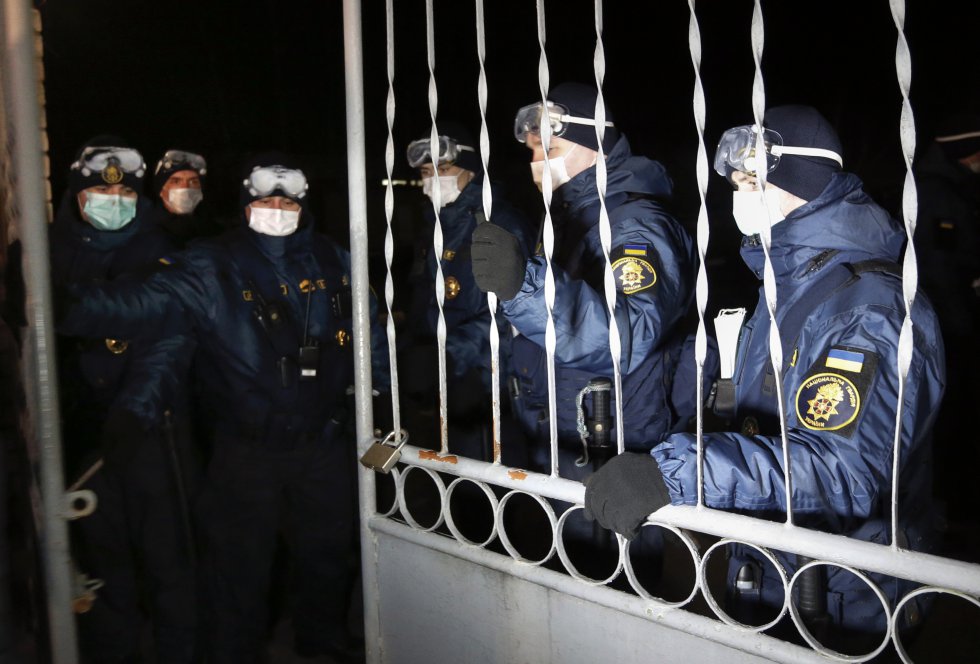 Agentes de la Guardia Nacional ucrania cierran el acceso al centro en el que están en cuarentena los ciudadanos evacuados de Wuhan por el coronavirus.