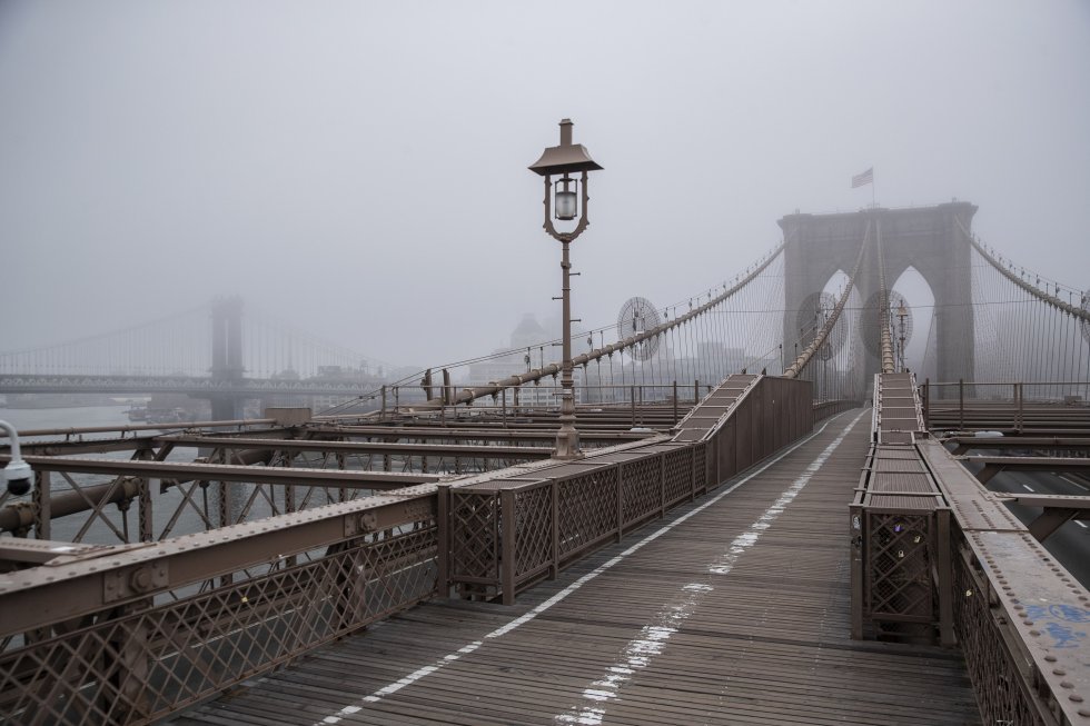 La niebla envuelve el horizonte de Manhattan mientras el puente de Brooklyn se encuentra casi vacío de tráfico peatonal.