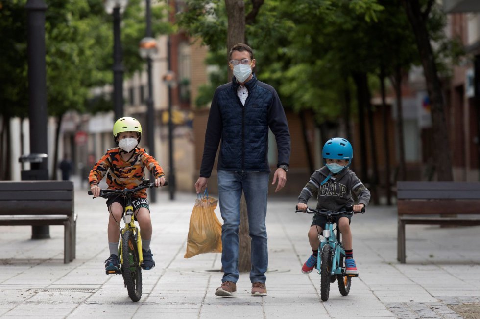 Unos niños en bicicleta pasean con su padre en la plaza Navarra de Huesca.