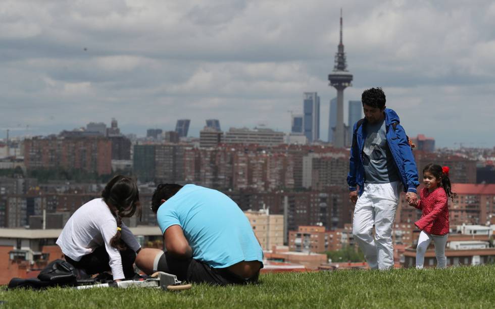 Familias disfrutan del buen tiempo en un parque de Madrid.