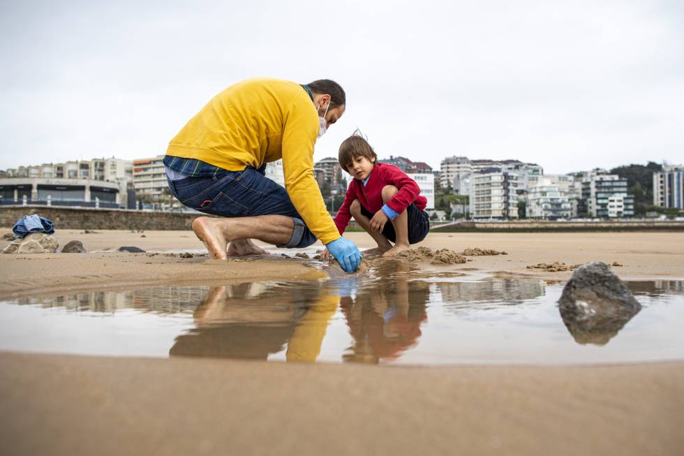 Un niño juega con su padre en una playa de Santander.