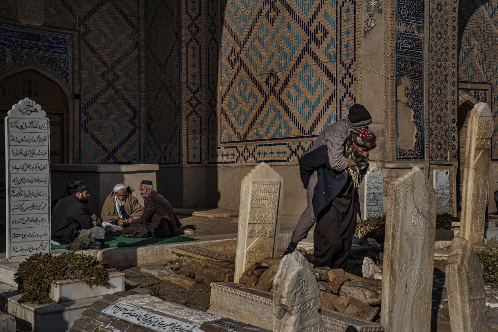 Un grupo de hombres come (izquierda) mientras otro carga a un anciano a la espalda (derecha) en el santuario sufí de Gazar Gah, cerca de Herat, en Afganistán. Durante el gobierno talibán, el sufismo estuvo prohibido, pero en muchas zonas está resurgiendo.