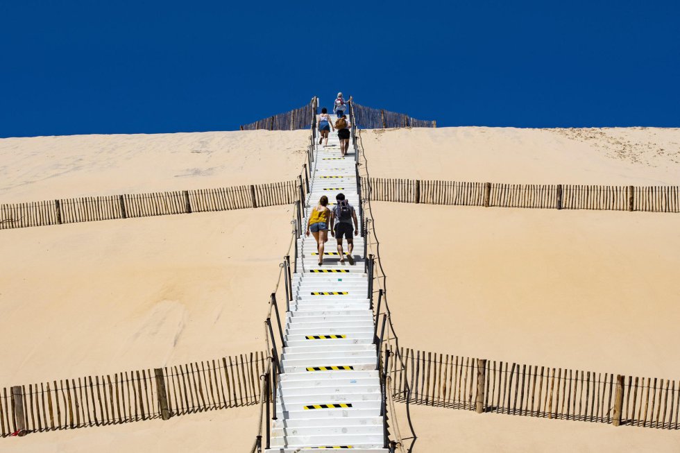 Un grupo de gente asciende por una escalera por la gran Duna de Pilat, cerca de Burdeos (Francia), que fue cerrada el 17 de marzo de 2020 debido a la pandemia de coronavirus.