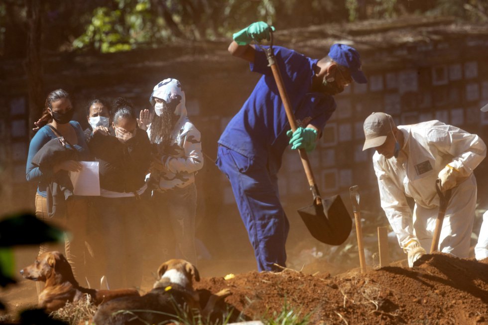Dos sepultureros echan tierra sobre el ataúd de una víctima de coronavirus mientras sus familiares lloran su pérdida, en un cementerio de Vila Formosa de São Paulo (Brasil).