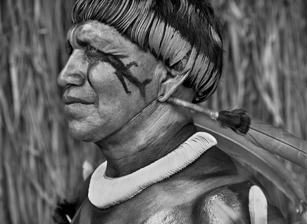 Os povos indígenas da Amazônia são os guardiões da selva, os guardiões de uma herança inestimável da humanidade. No entanto, sua sobrevivência está em risco.  Tsaná  Este homem é um cantor de música tradicional do Alto Xingu, um presente que ele herdou de seu pai, o maestro Tagukagé. Ele usa um colar de conchas de caracóis e tem o corpo pintado de urucum.