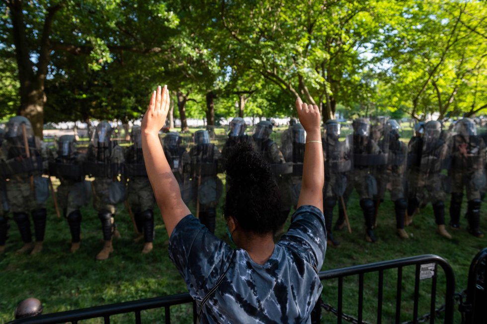Una manifestante levanta los brazos frente a la Guardia Nacional a las afueras de la Casa Blanca. En un mensaje a la nación, el presidente Donald Trump amenazó con desplegar al Ejército en el resto del país si los gobernadores no frenan la violencia.
