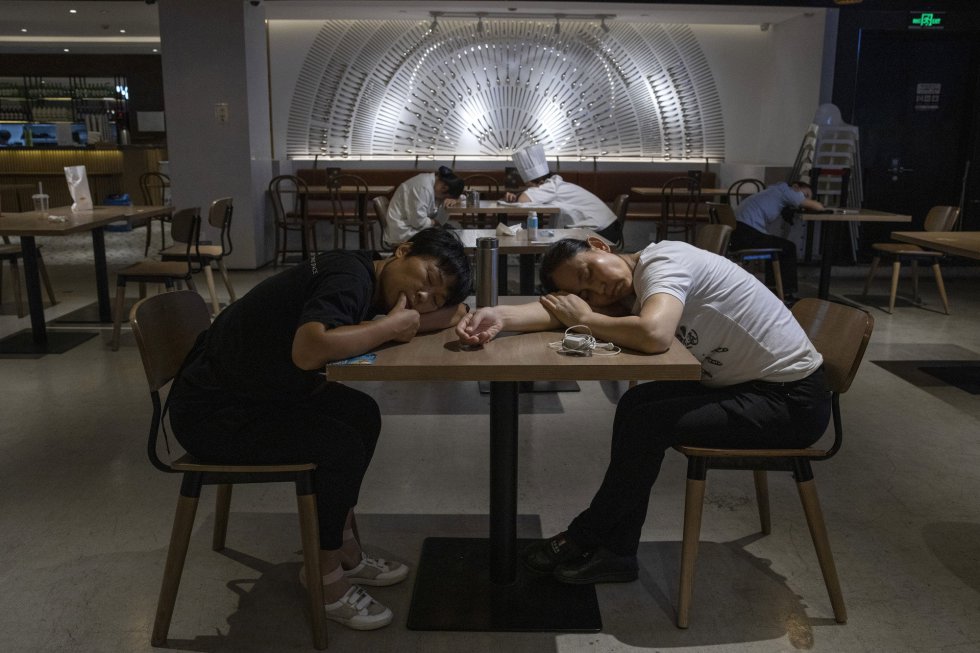 Dos empleados de un restaurante descansan sobre una mesa, en un centro comercial de Pekín (China). El Ministerio de Salud de China ha confirmado este martes seis nuevos casos de coronavirus importados pero ninguno de transmisión local, por lo que el cómputo global del país ha ascendido hasta los 83611 positivos.