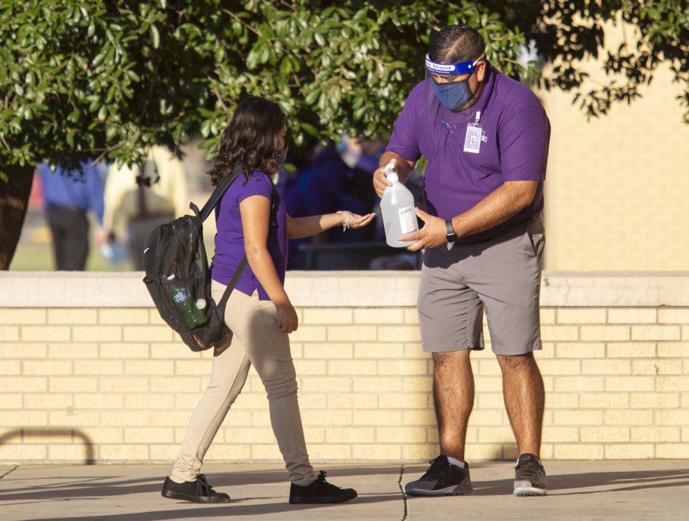 Un profesor le ofrece gel desinfectante a una alumna durante el periodo de adpatación previo a la vuelta a las clases presenciales en la escuela Bowie Middle, en Odessa (Texas).