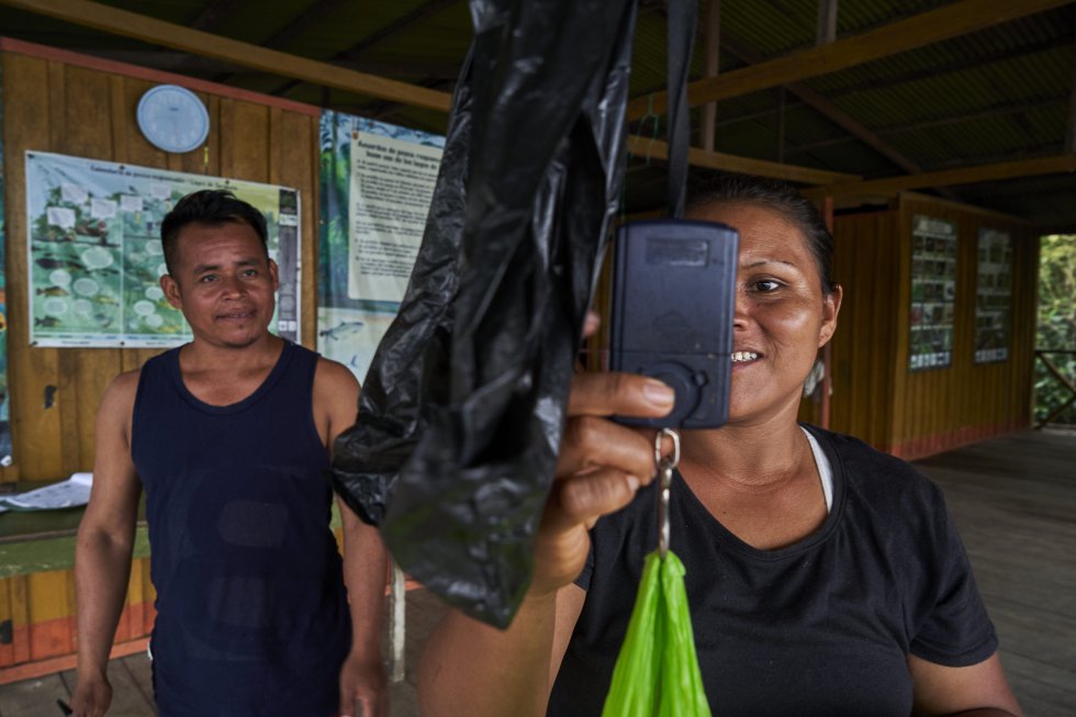 Lilia pesa parte del pescado de una embarcación durante una inspección de control, en la balsa de control, ubicada en la entrada del lago Tarapoto. Decenas de especies protegidas están siendo monitorizadas, y Lilia dirige con valentía y autoridad indiscutida las operaciones de la balsa, desde donde se realiza el recuento de la población de distintas especies de peces y mamíferos acuáticos como nutrias, manatíes, y delfines.