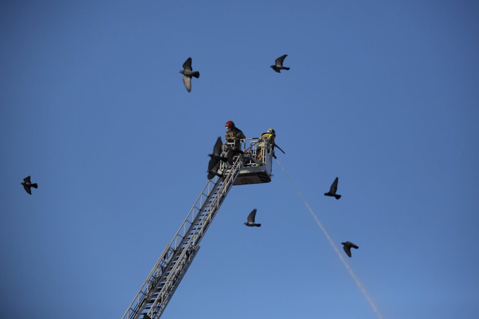 Alguns bombeiros resfriam o prédio.