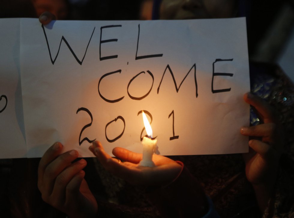 Uma menina acende um cartaz com uma vela que diz "Bem-vindo 2021" (bem-vindo 2021), em Lahore (Paquistão).