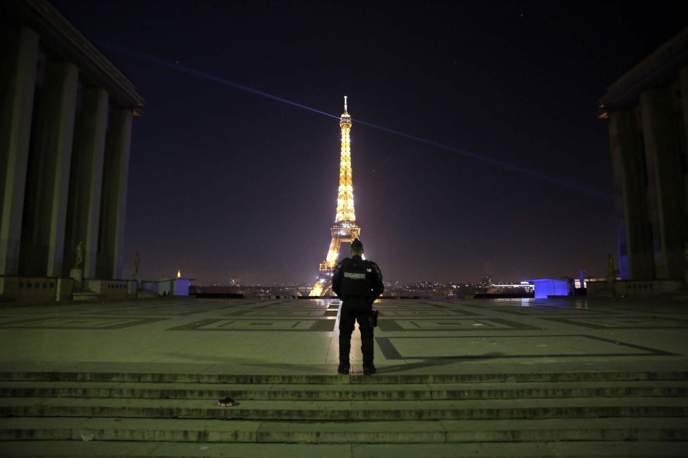 Um policial patrulha a praça Trocadero em Paris.  Ao fundo, a Torre Eiffel.