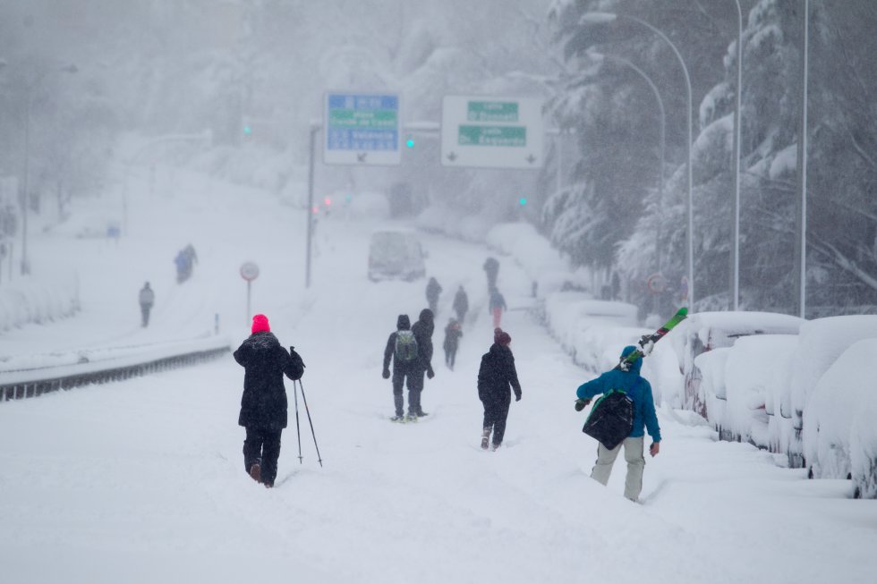 El ministro del Interior, Fernando Grande-Marlaska, ha asegurado que han sido rescatadas casi 1.500 personas que permanecían atrapadas en sus coches por la nieve en la Comunidad de Madrid desde la tarde del viernes. En la imagen, varias personas caminan por la M-30 cubierta de nieve, en la capital.