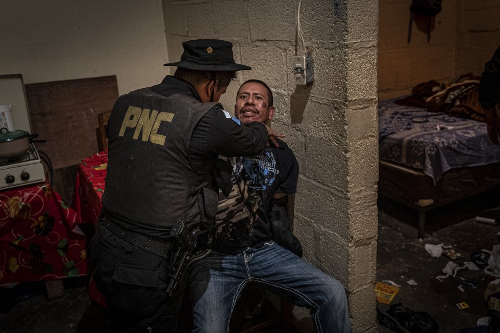 Um agente detém um membro da seção Crazy Gangsters do Barrio 18 durante uma busca em sua casa no bairro de Santa Faz, na Cidade da Guatemala.