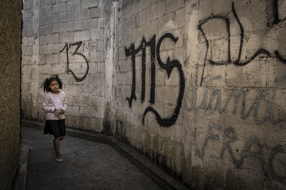 Uma garota atravessa um beco na Cidade da Guatemala marcado com pichações da Mara Salvatrucha, a gangue mais poderosa do país junto com seu maior rival, o Barrio 18.