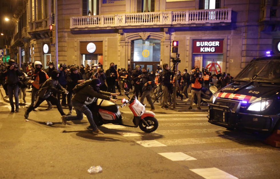 Un manifestant pousse une moto vers un véhicule Mossos, ce mercredi à Barcelone.