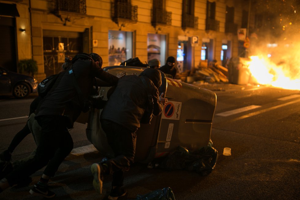 Un groupe de manifestants déplace une poubelle lors d'altercations dans le centre de Barcelone.