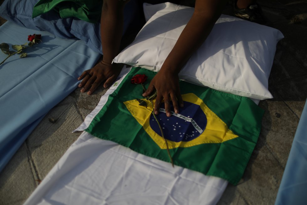 Un manifestante sostiene una bandera de Brasil junto a colchones con rosas que simbolizan las más de 300.000 víctimas de coronavirus.