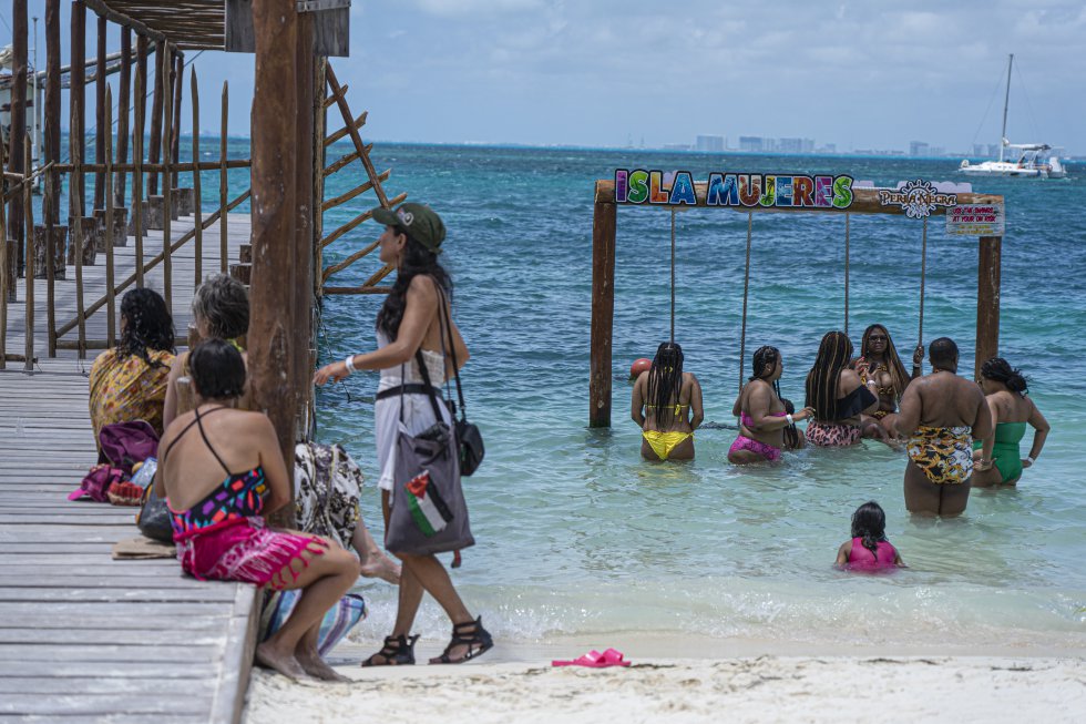 Turistas se bañan en las playas de Isla Mujeres a unos metros de donde se encuentra el barco 'La Montaña', horas antes de la salida de los zapatistas rumbo a Europa.