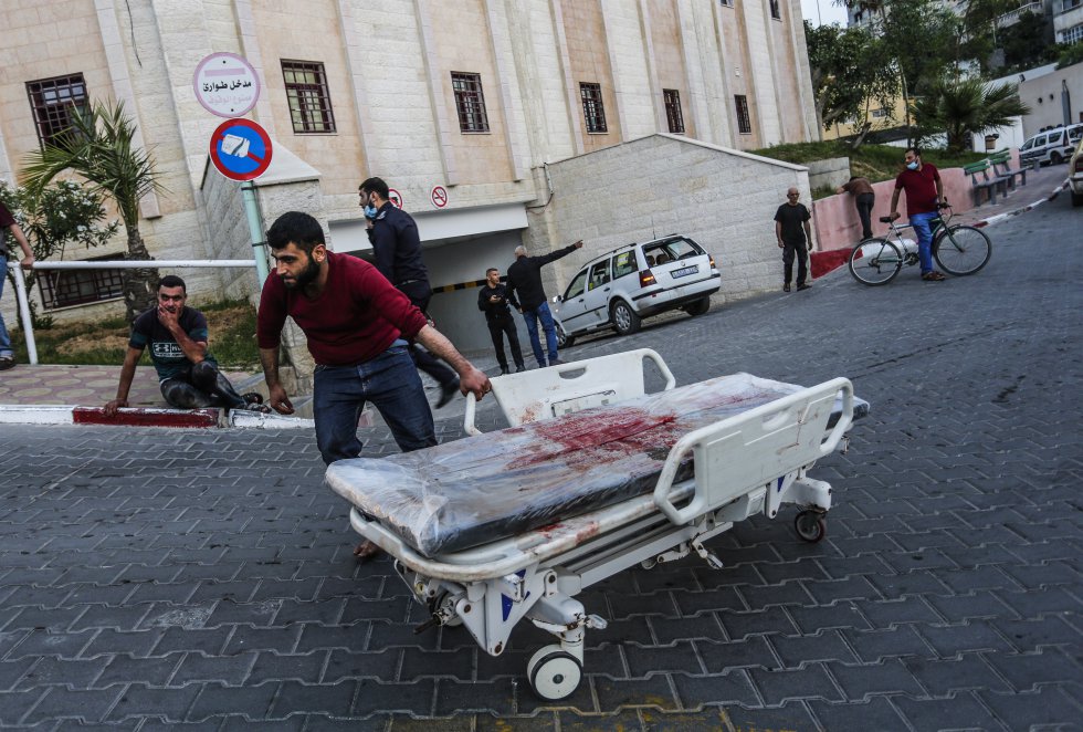 Una persona trasporta una camilla ensangrentada tras los bombardeos israelís sobre la Franja de Gaza.