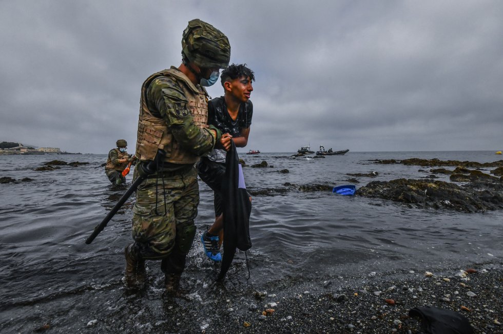 Un soldado del Ejército de Tierra ayuda a un menor marroquí a salir del agua después de que haya cruzado la frontera española nadando. 