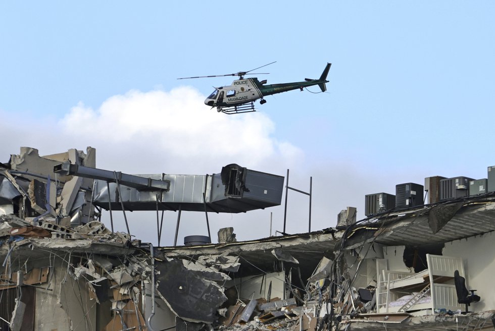 Un helicóptero sobrevuela los restos del edificio, este jueves. El alcalde de Surfside, Charles Burckett, confirmó en una rueda de prensa que una de las primeras personas rescatadas murió al llegar al hospital y subrayó que es posible que haya más muertos, pues la parte este del edificio se derrumbó planta sobre planta y puede haber personas aplastadas entre las capas.