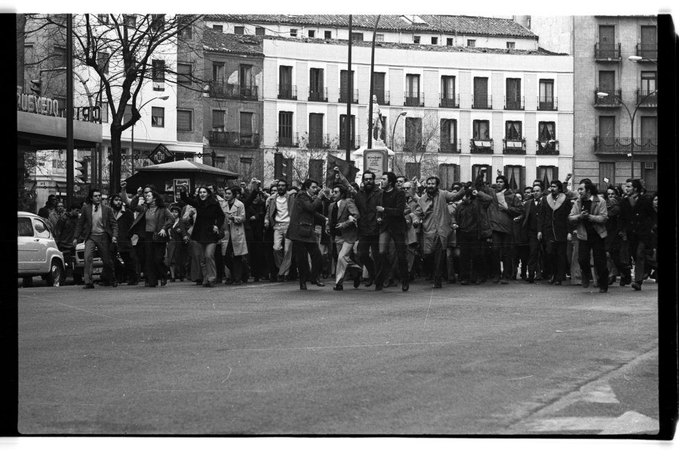 Plaza de Quevedo de Madrid, 13.00 del 5 de diciembre de 1975. En el 50º aniversario de la muerte del fundador del PSOE, Pablo Iglesias, militantes socialistas protagonizan un 'salto' en plena calle de Fuencarral con lanzamiento de panfletos. Todavía quedaban banderas con crespones negros en algunos balcones por la muerte de Franco. En el centro de la imagen se ve a Javier Solana, luego ministro de Cultura en el primer Gobierno de Felipe González con el PSOE.