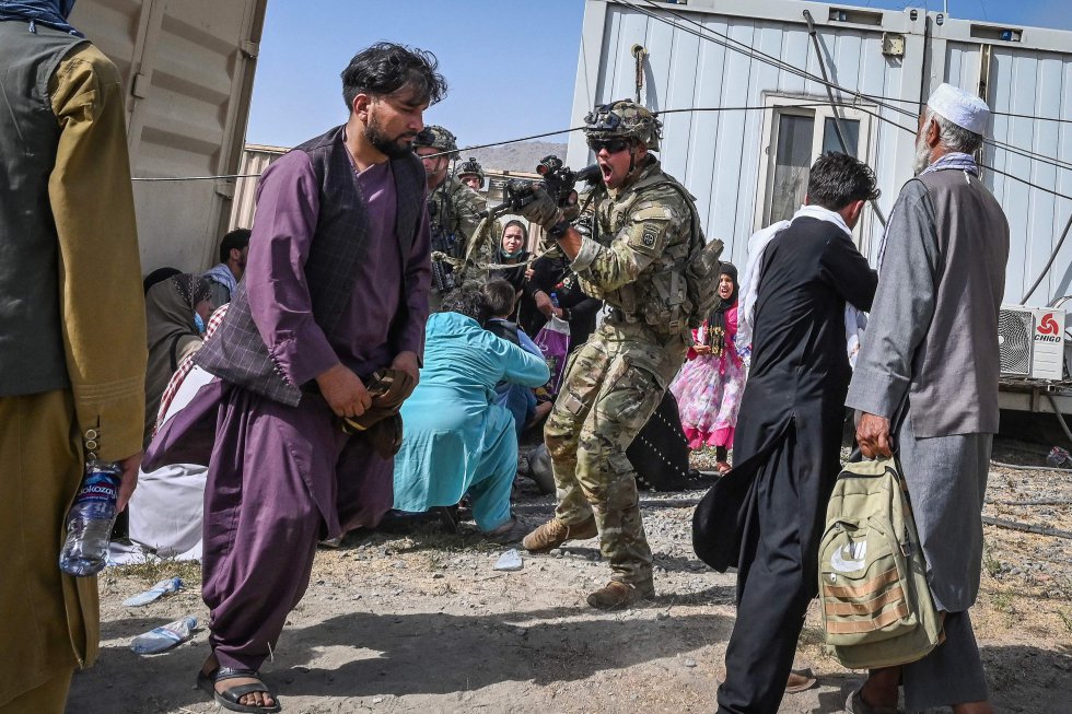 Un soldado estadounidense (en el centro) apunta con su arma hacia un afgano en el aeropuerto de Kabul, este lunes.