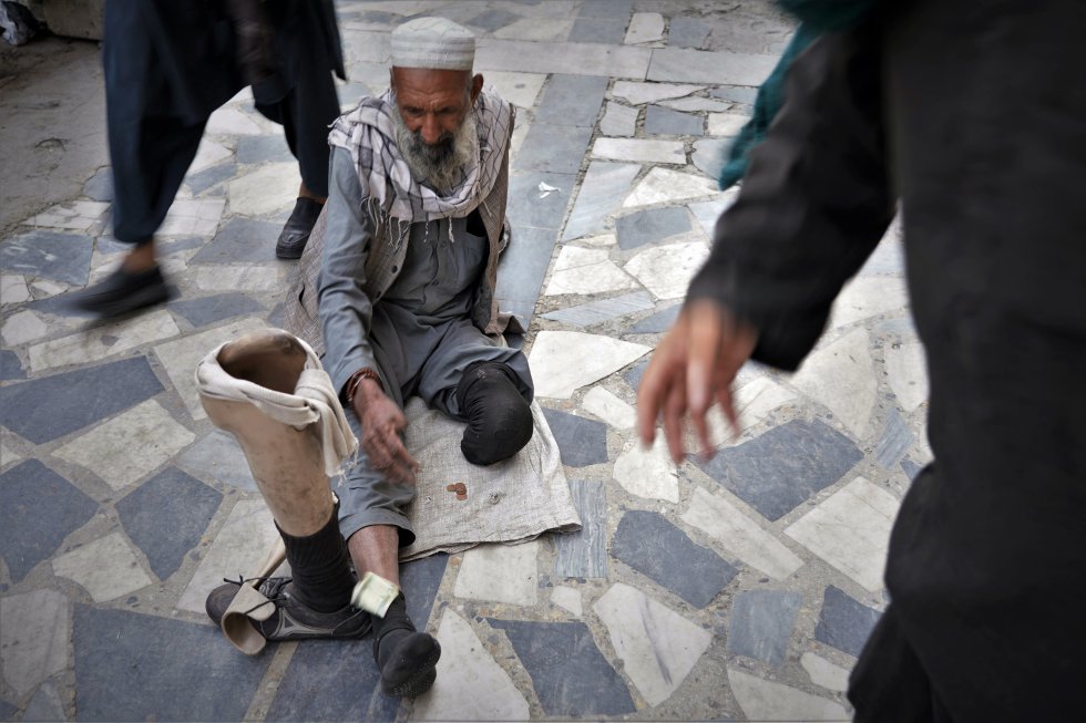 Una mujer lanza un billete a un hombre que mendiga cerca del bazar Mandawi de Kabul, el 10 de octubre. Miles de personas, muchas de ellas amputadas de guerra, viven de lo que consiguen cada día en las calles de la capital.