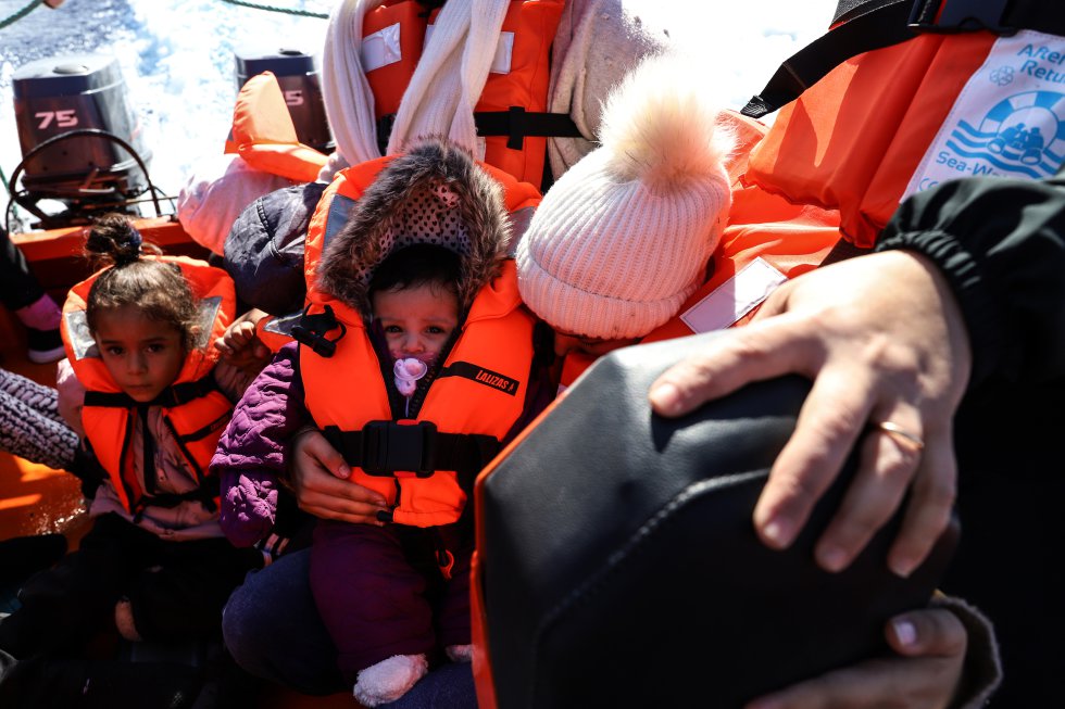 Migrantes sentados, entre los que hay varios niños, en una lancha semirrígida del 'Sea Watch 3'. Acaban de ser rescatados.