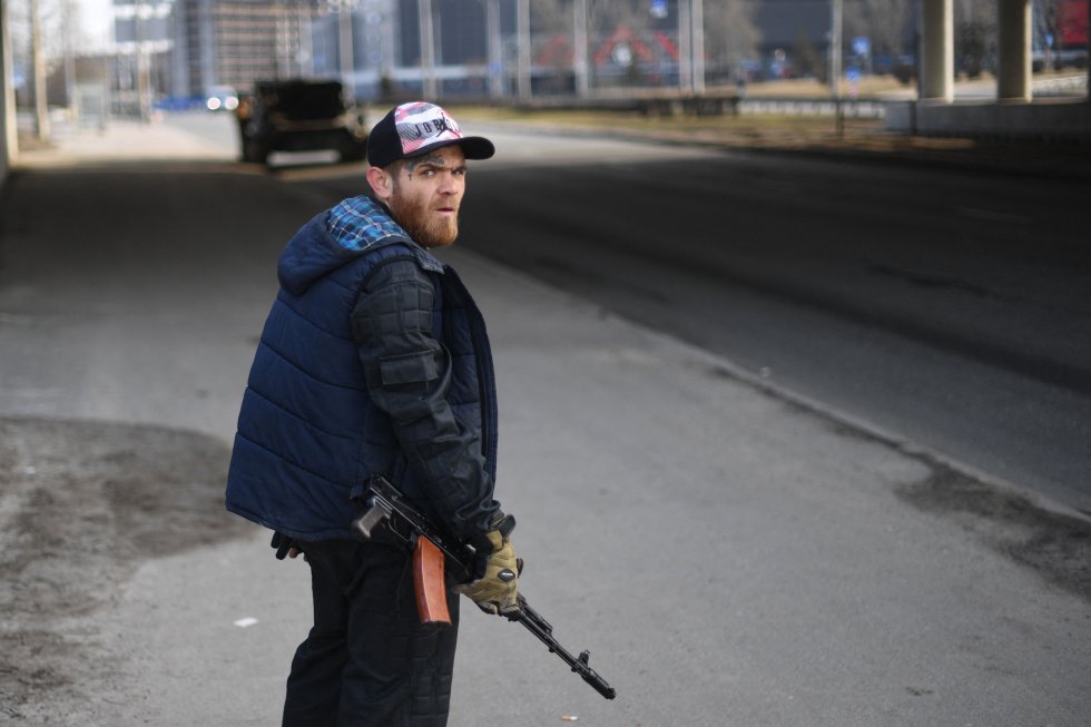 Un hombre sostiene un rifle en una carretera principal que conduce a Kiev.