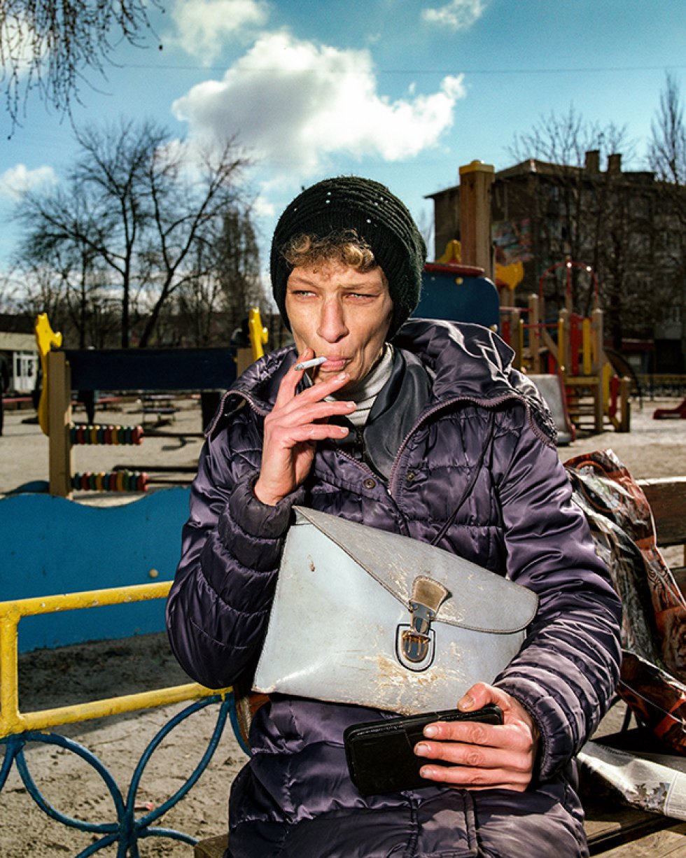 Mujer fumando en un banco en Myrnograd, Donetsk, 2021. 