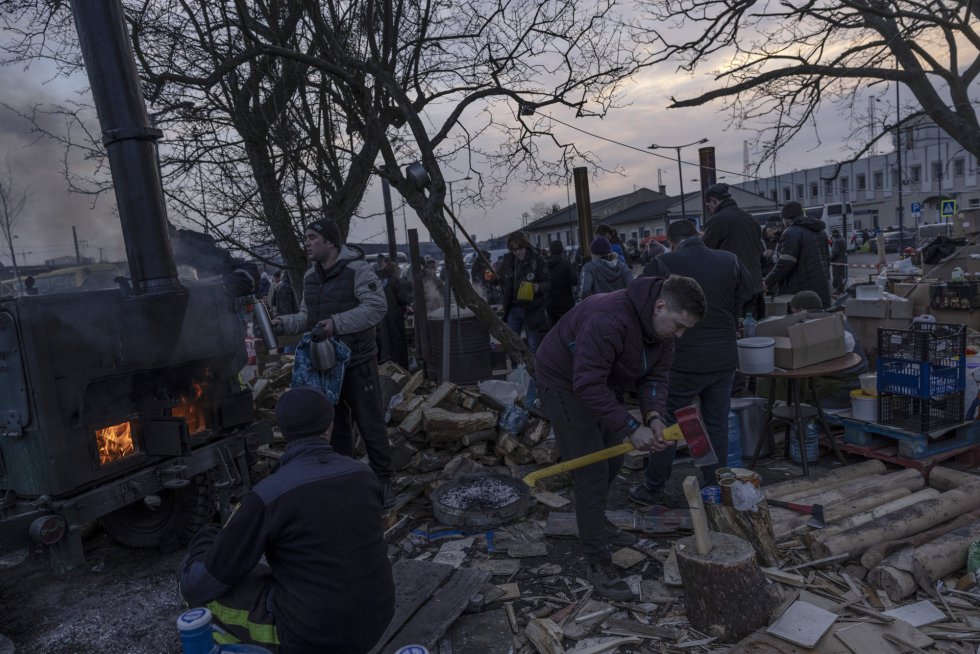 Një burrë pret dru zjarri ndërsa vullnetarët ndihmojnë në sigurimin e ujit të nxehtë dhe ushqimit rreth stacionit të trenit në Lviv. Komisioneri i Lartë i Kombeve të Bashkuara për Refugjatët, Filippo Grandi, konfirmoi në Bukuresht se numri i refugjatëve që kanë ikur nga Ukraina ka kaluar tashmë një milion njerëz dhe mbërritjet do të vazhdojnë të rriten "nëse veprimet ushtarake" nuk ndalen.