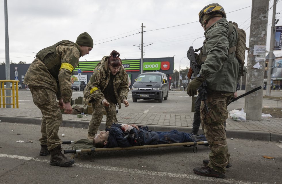 Militares ucranios ayudan a un herido en Irpin, cerca de Kiev. La televisión Ukraine 24 mostró a un combatiente del regimiento Azov de la Guardia Nacional que sostuvo que las fuerzas rusas que han rodeado la ciudad portuaria de unos 400.000 habitantes seguían bombardeando las zonas que, en teoría, deberían estar protegidas por el alto el fuego.