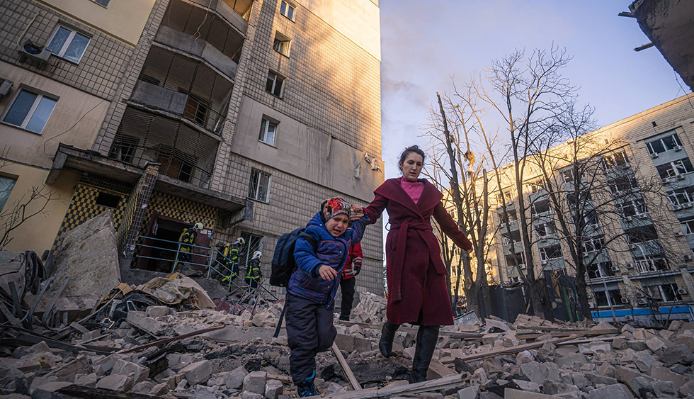 Una mujer y un niño salen de un edificio bombardeado por las tropas rusas este miércoles en Kiev. Los ministros de Defensa de la Alianza Atlántica se reúnen hoy en Bruselas antes de la cita de presidentes de la semana que viene, a la que acudirá el estadounidense Joe Biden.