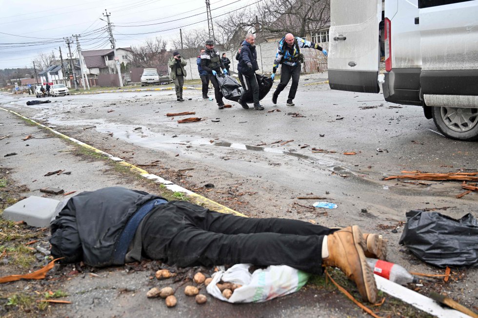 Un grupo de civiles traslada un cadáver a una furgoneta en Bucha, el domingo. En primer plano, el cuerpo sin vida de un hombre. La ONG Human Rights Watch afirma haber documentado entre el 27 de febrero y el 14 de marzo varios casos en que las fuerzas rusas cometieron lo que constituirían crímenes de guerra contra civiles en zonas ocupadas en las regiones de Chernihiv (norte), Járkov (noreste) y Kiev.