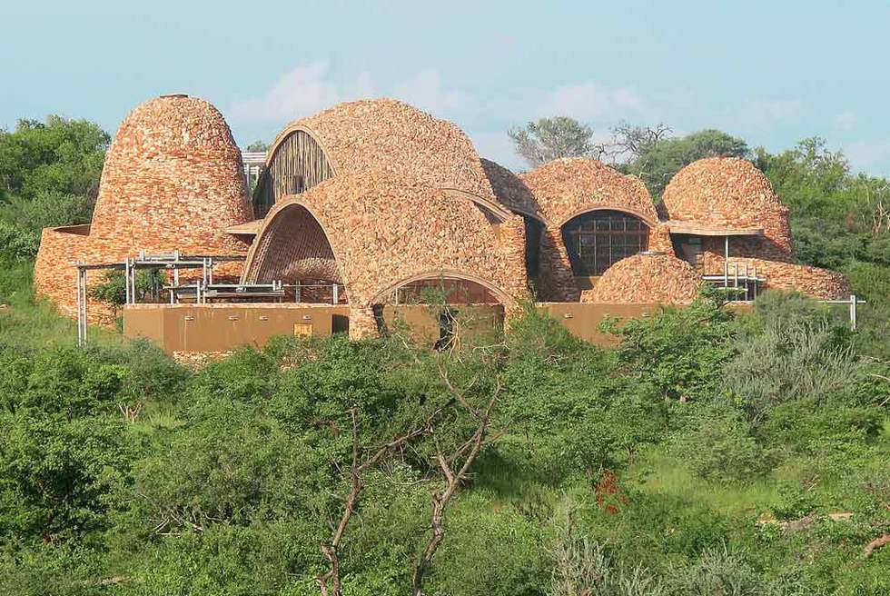 Las líneas ondulantes y el uso de materiales locales -como los trozos de roca descompuesta que cubren las bóvedas- están inspirados en el paisaje del parque nacional de Mapungubwe (Suráfrica), en una de cuyas mesetas está ubicado este Centro de Interpretación proyectado por Peter Rich ( www.peterricharchitects.co.za ).