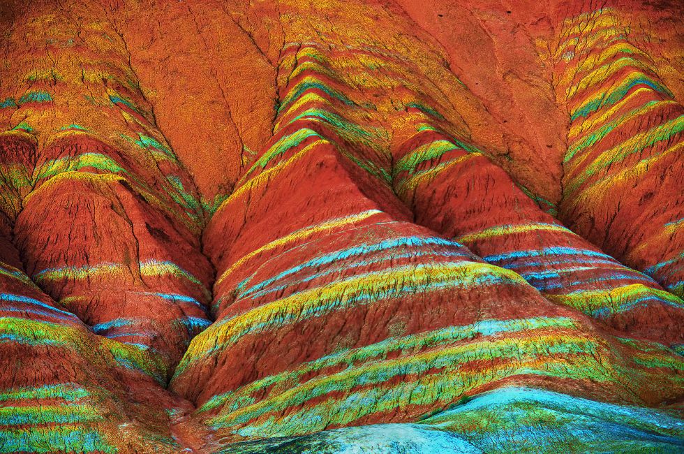 Parecen olas pintadas en la ladera de la montaña, pero en realidad se trata de capas de sedimentos de piedra arenisca y minerales que se depositaron en esta zona del norte de China hace más de 24 millones de años y que fueron modelados por los movimientos tectónicos y la erosión. Son el elemento más distintivo del parque nacional geológico de Danxia Landform, en la provincia china de Gansu.