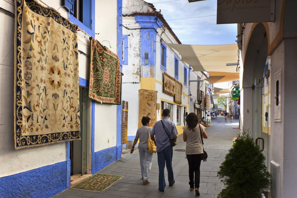 A unos 20 kilómetros al norte de Évora la pequeña localidad de Arraiolos es famosa por sus exquisitas alfombras (tapetes), tejidas a mano desde el siglo XII. Medio pueblo está implicado en su producción y paseando por sus calles es fácil dar con personas que las tejen frente a sus casas. Se puede echar un vistazo a las antiguas salas de tintado en la plaza principal. Arraiolos, pueblo de larga historia, podría pasar como un modelo de localidad tradicional del Alentejo, con casas encaladas con toques azules y tejados de terracota, ruinas de un castillo dominando la localidad y una iglesia de sencilla fachada blanca que oculta un hermoso interior, con altares dorados y paredes cubiertas de azulejos antiguos.