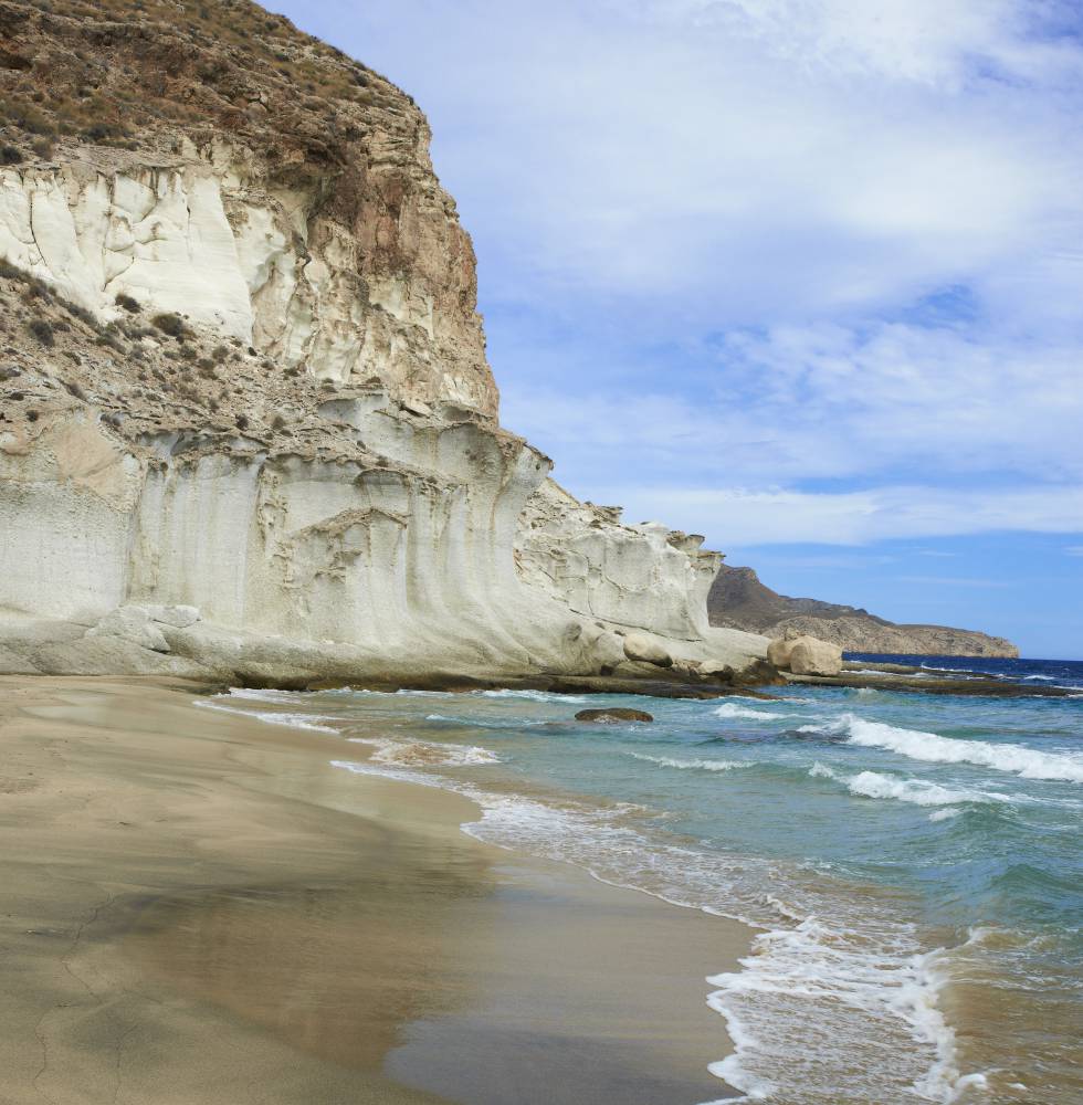 A medio camino entre Agua Amarga y la cala del Plomo, conserva la virginidad de siempre en el parque natural del Cabo de Gata-Níjar. En ella asombran, en su flanco izquierdo, erosiones eólicas y marinas labradas en la piedra arenisca. A mano derecha queda una suerte de oquedad donde reverbera el oleaje. Las planchas rocosas desde las que zambullirse en un mar nítido y los colores cenicientos de la arena fina dan a este enclave un aire de magia y misterio. Acceso: 300 metros antes de la cala del Plomo está el arranque de la senda de 1,7 kilómetros (unos 25 minutos) a la cala de Enmedio. Más incómodo resulta hacerlo desde Agua Amarga (45 minutos).