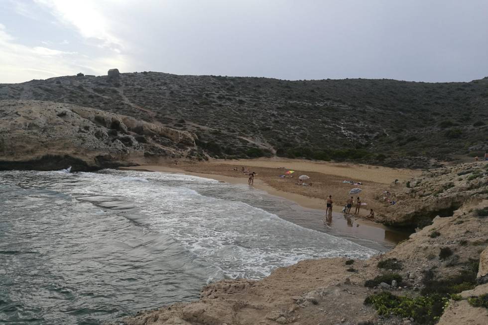 El parque regional de Calblanque es célebre por sus playas, aunque mucho menos por esta calita de campanillas encastrada entre Punta Espada y Punta Negra. Cala Déntoles —o cala Dorada— cobra un valor inusitado por su variedad cromática: del negro en los restos mineros al dorado en la arena. Y además lirios marinos (en floración primaveral), cornicales y algún palmito. Al pie del cerro del Atalayón sorprendemos a un pintor con su caballete retratando la bella escena. El baño, como en toda esta franja de costa abierta al levante, entraña peligros, por lo que hay que ir con tiento. Al regreso, el mirador de Punta Negra ya forma parte del imaginario colectivo costero de Murcia. Acceso: en Calblanque, tras rebasar las salinas, aparcamos en cala Magre. A 600 metros, después de un repecho, alcanzamos los Déntoles. A partir de junio solo se puede acceder en autobús público. El sendero desde cala Reona (unos 2 kilómetros) cuenta con un tramo complicado con cuerdas para sujetarse.