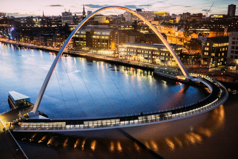 Más que un puente, es una manifestación arquitectónica: este enorme arco de acero que une las dos orillas del Tyne es el primer puente basculante del mundo. Su recorrido rotativo —pero fijo en sus dos extremos— proporciona a peatones y ciclistas una divertida conexión entre Gateshead y Newcastle, a través de la rehabilitada zona portuaria. Además, como todo el conjunto —el camino peatonal y el arco de contrapeso, de 50 metros de altura— oscila sobre los puntales, permite el paso de barcos grandes con una maniobra de bajo consumo. Muchos lo llaman el ‘Winking Eye Bridge’ (puente del ojo guiñado), por su forma y por cómo se eleva.   El puente  enlaza el artístico barrio de Quays, que acoge, en la orilla sur, el recinto musical The Sage y el BALTIC Centre for Contemporary Art, con el de Quayside de Newcastle, en la orilla norte.