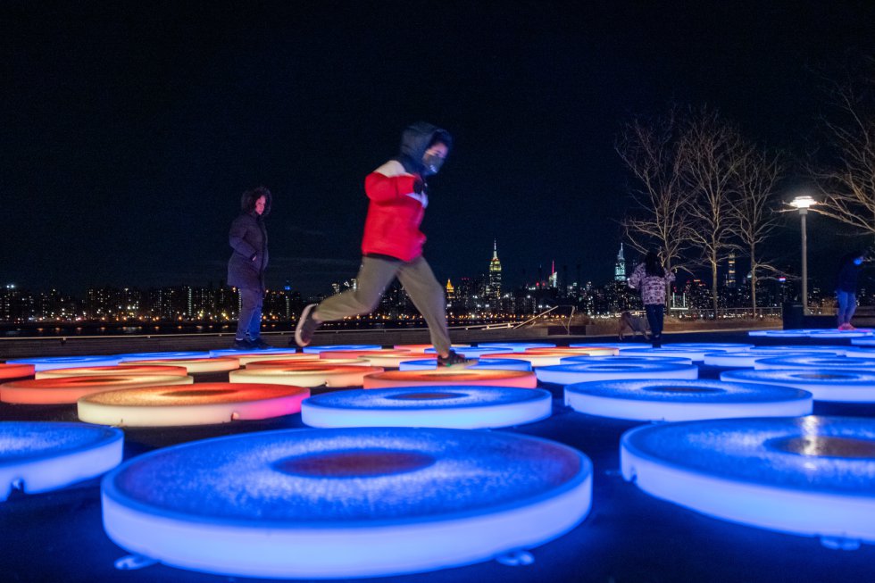 'Reflect' é uma nova instalação de arte no Domino Park, um parque público de cinco hectares que segue o curso do East River no bairro de Williamsburg em Brooklyn, Nova York.  Criada pela artista americana Jen Lewin, a obra consiste em três anéis concêntricos com plataformas feitas de luzes interativas que respondem aos passos dos visitantes, liberando flashes de luz que criam uma composição em constante mudança.  “A instalação encorajará os nova-iorquinos a fazer uma pausa para um momento de reflexão e descoberta e inspirará a conexão enquanto a cidade entra em uma nova era de esperança e recuperação”, explicam eles do parque (dominopark.com).  Aberto das 8h00 às 22h00 (até 15 de abril), durante o dia sua superfície reflete o céu e o meio ambiente, e à noite,  a escultura ganha vida conforme os espectadores se movem através de seus painéis, criando um espetáculo multicolorido com o horizonte de Manhattan do outro lado do rio.  Uma forma de se divertir no Brooklyn ao ar livre e respeitando distâncias seguras.