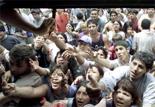La creciente y en muchos casos nueva pobreza en Argentina detonÃ³ en forma de miles de personas que se echaron a la calle en busca de alimento. En la imagen, el dueÃ±o de un supermercado reparte comida. (REUTERS)