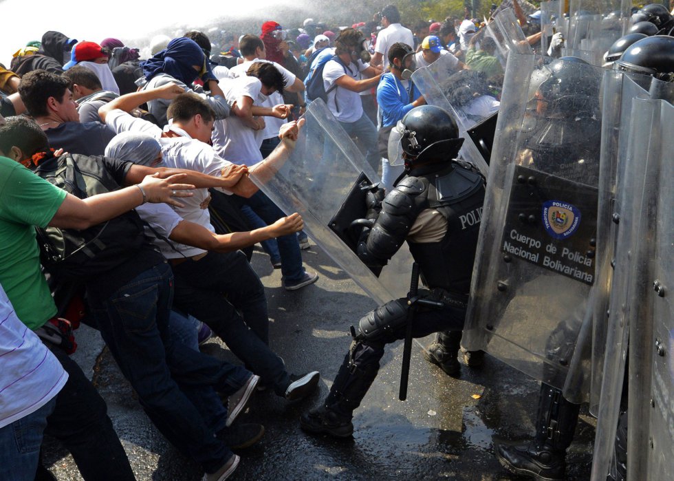 En un sector de esa ciudad industrial, La Isabelica, se registraron tres muertes por disparos. Entre los fallecidos se cuenta un oficial de la Guardia Nacional, Ranzor Bracho, de 36 años de edad. En la imagen, un grupo de estudiantes se enfrenta a la policía durante la protesta en Caracas, 12 de marzo de 2014.