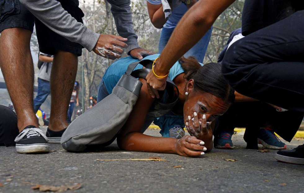 Las cacerolas se dejaban escuchar con estruendo esta noche del miércoles en Caracas, en gesto de protesta al cierre de una de las jornadas más cruentas desde que, hace justo un mes, se iniciaron las movilizaciones –estudiantiles en su origen- que sacuden a Venezuela. En la imagen, una joven es ayudada tras ser gaseada durante la protesta en Caracas (Venezuela), 12 de marzo de 2014.