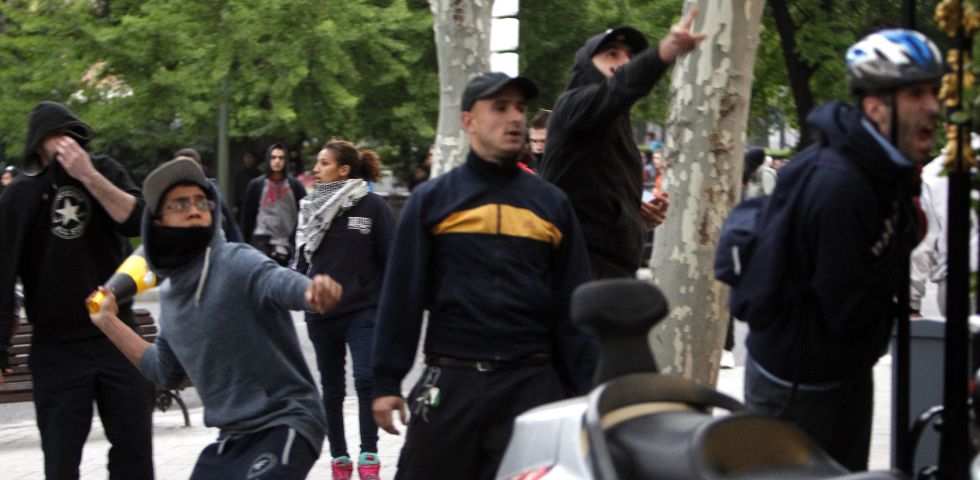 Jóvenes lanzan objetos a la policía durante la protesta ante el Congreso de los Diputados.