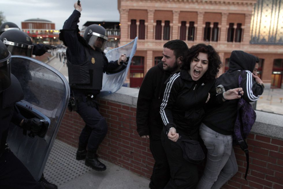 La policía antidisturbios golpea a uno jóvenes en las proximidades de la estación de Atocha, Madrid, durante la protesta del 25A.
